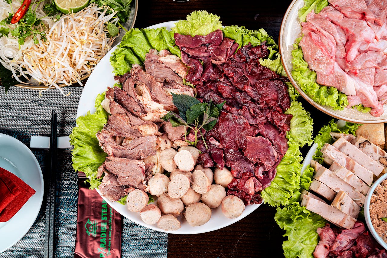 Top view of a Vietnamese hot pot featuring assorted meats with fresh vegetables, perfect for a communal meal.